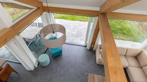 A modern interior with a large window, a hanging light fixture, a sofa, and a small round table. - Duinzicht Renesse by Interhome (Renesse)