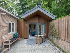 Relax in a serene outdoor patio with a comfortable bench and wicker table.