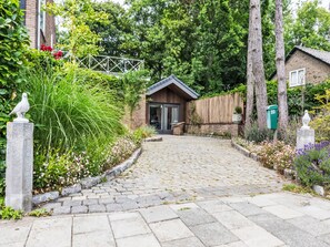 Enter a serene home surrounded by lush greenery and a charming cobblestone pathway.