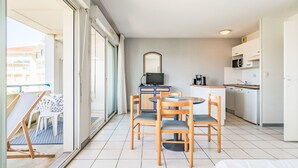 Ein modernes Hotelzimmer mit Balkon, einem Essbereich mit Holzkohle und einer Küche mit weißen Geräten sowie einem großen Spiegel an der Wand.