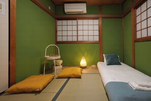 A traditional Japanese-style room with tatami flooring, a futon bed, a shoji screen, and a small table with a lamp. - Otabiya Noda (Osaka)