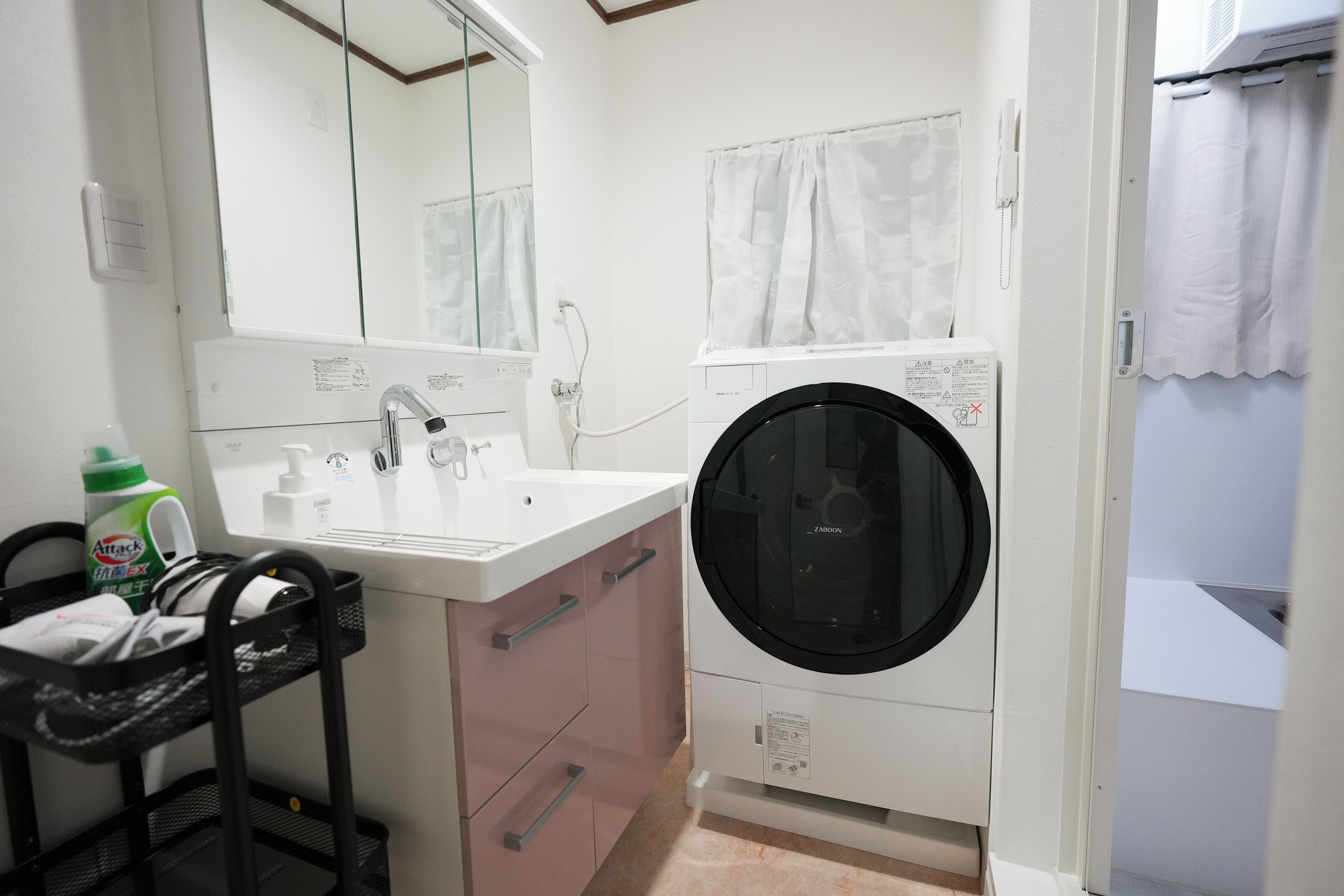 A bathroom with a sink, mirror, and a black washing machine.