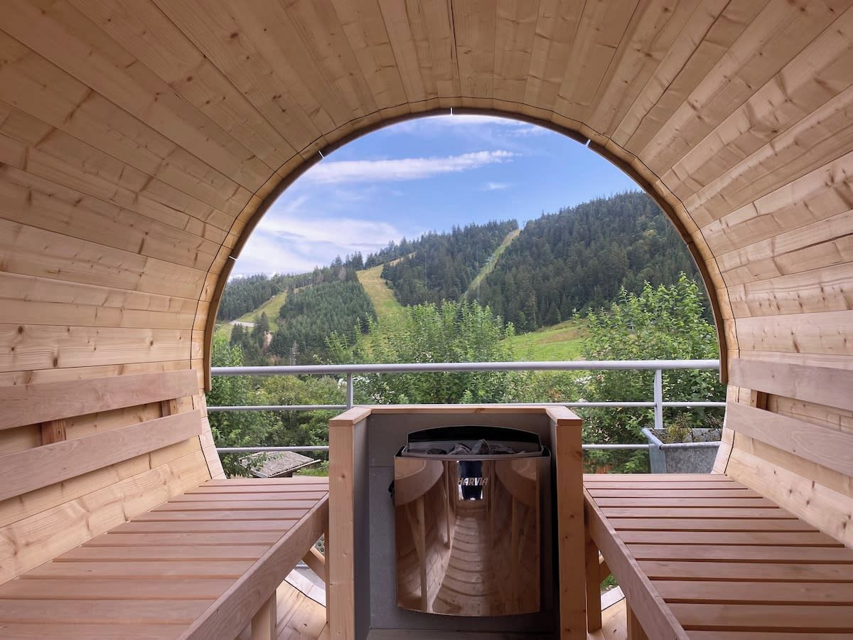 A wooden sauna with a view of a forested hillside.