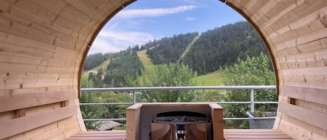A wooden sauna with a view of a forested hillside.
