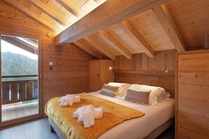 A wooden cabin bedroom with a bed, pillows, and towels.