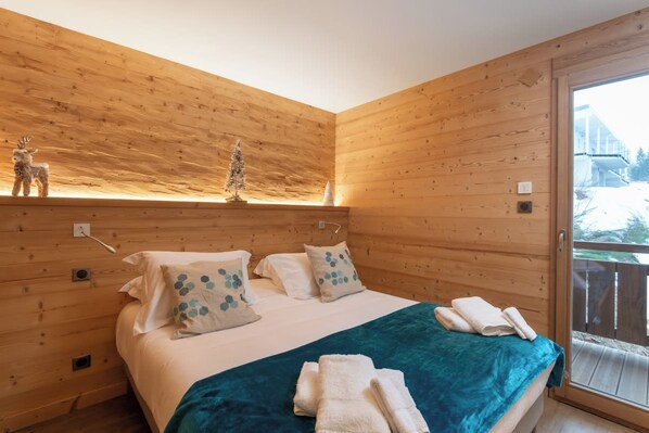 A wooden-paneled room with a bed, pillows, and a blanket.