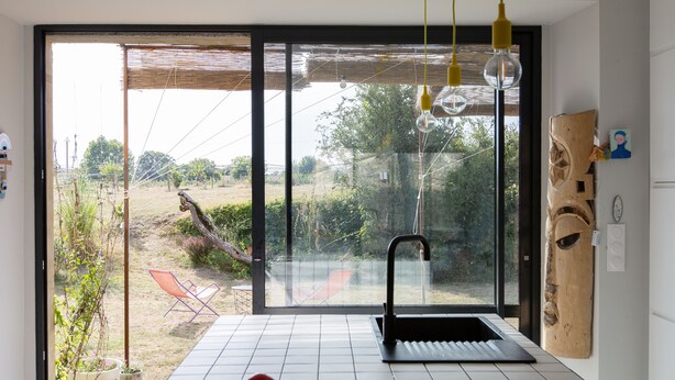 Una cocina con un ventanal grande, un lavabo y un frutero sobre la encimera.