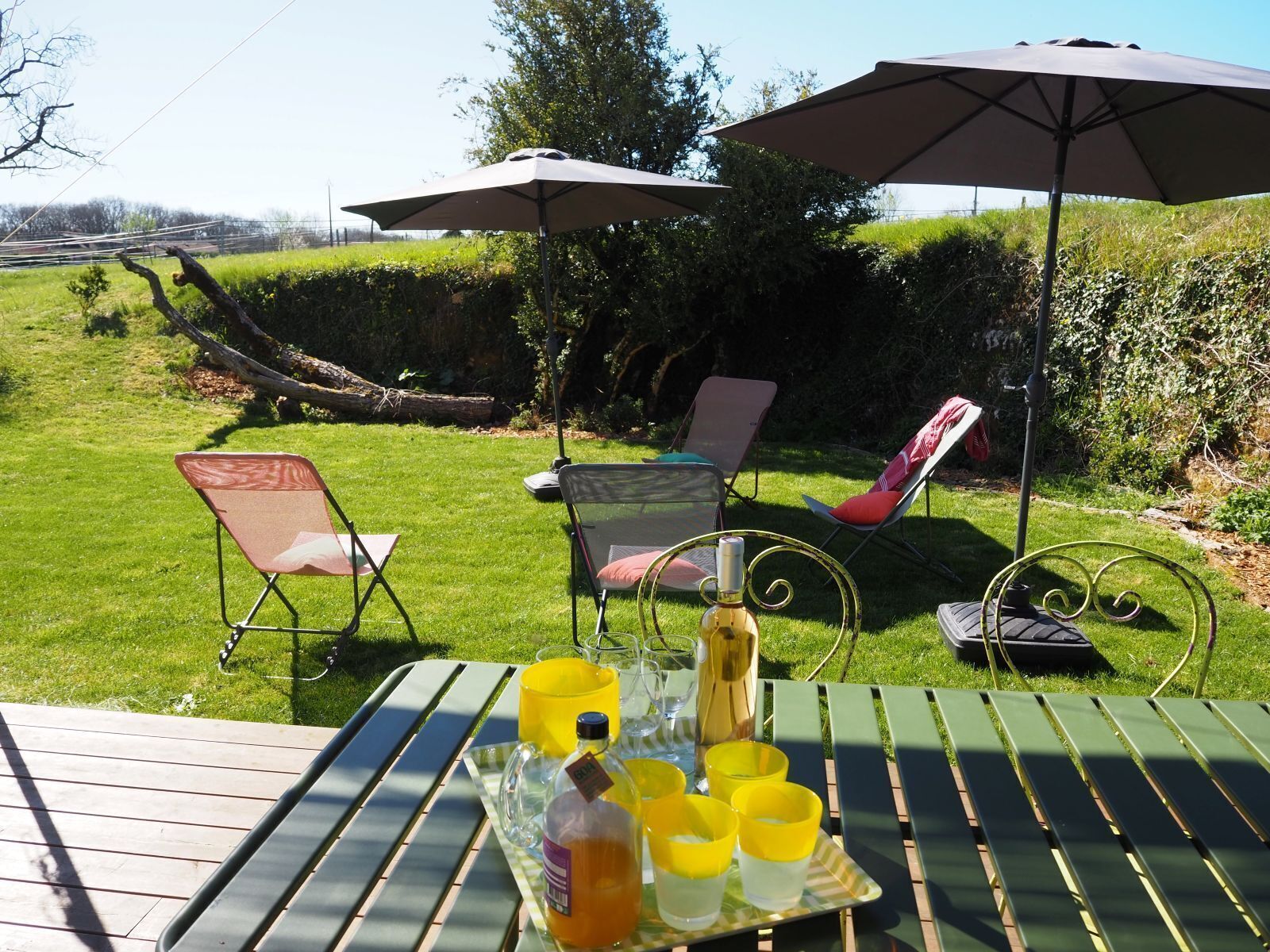 Un patio al aire libre con una mesa dispuesta para bebidas, rodeado de sillas y sombrillas.