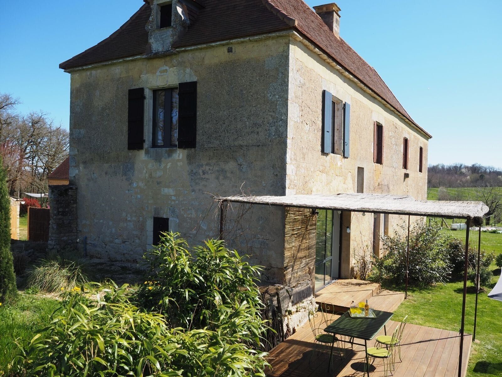 A rustic stone house with a covered patio and a table with chairs.