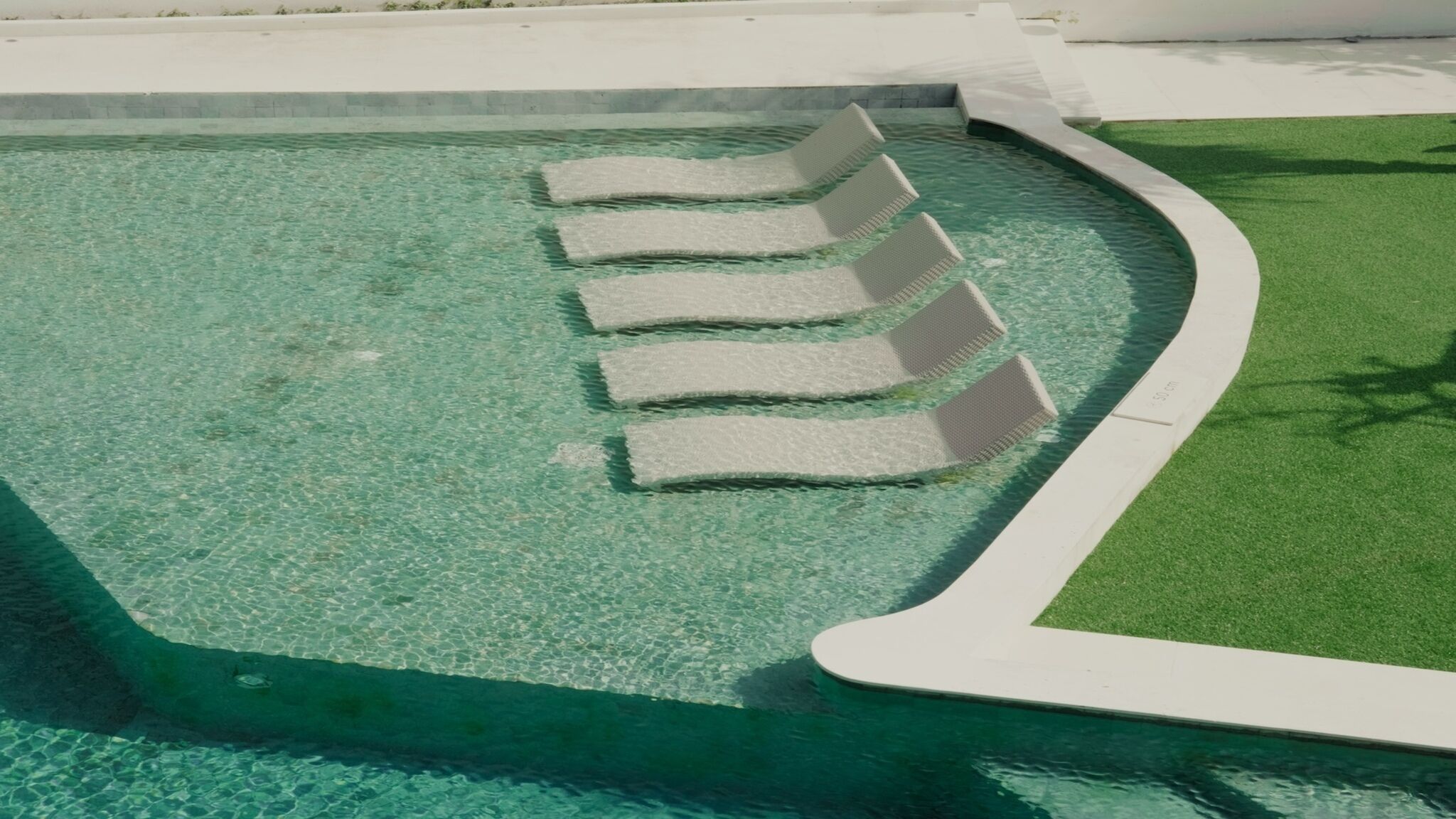 A swimming pool with clear water and a series of white floating steps leading into it.