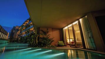 A modern hotel with a swimming pool, indoor/outdoor seating, and a view of the surrounding buildings.