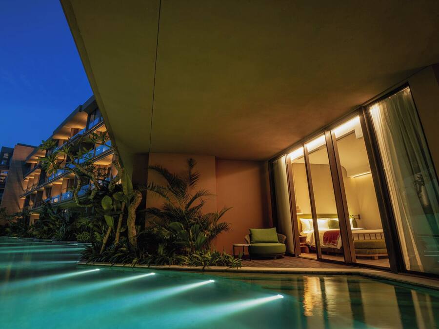 A modern hotel with a swimming pool, indoor/outdoor seating, and a view of the surrounding buildings.