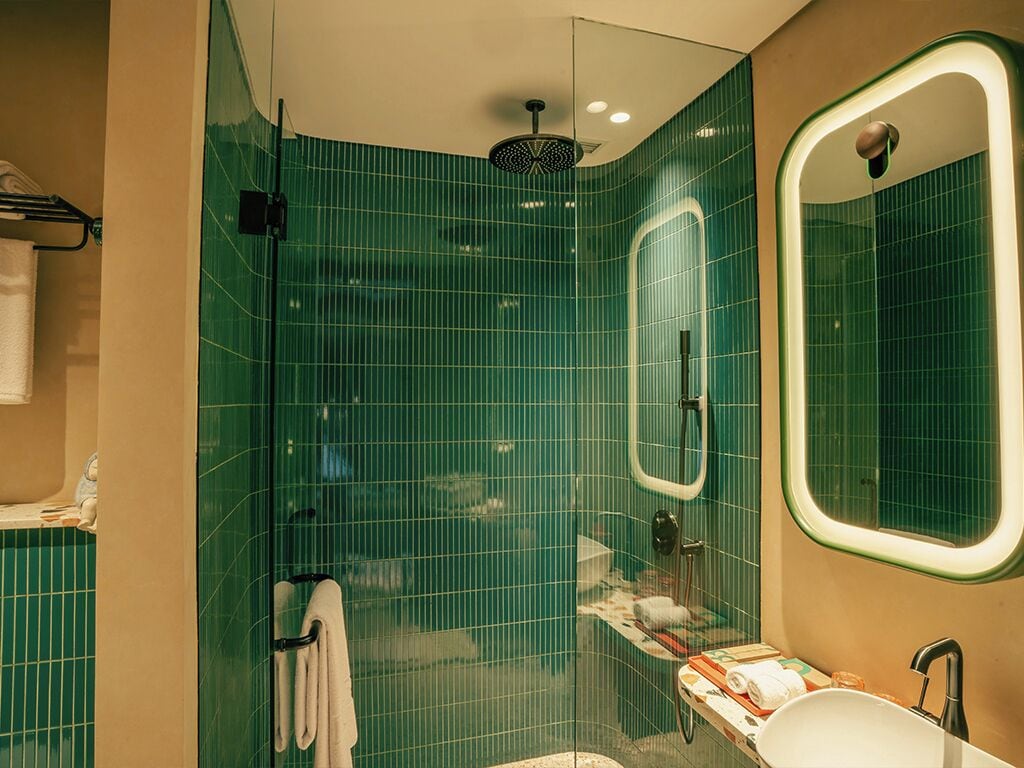 Un baño con cabina de ducha de vidrio, lavabo con espejo y toallero.