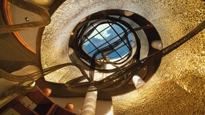 A spiral staircase with a circular skylight, a woven chair, and a white cylindrical column. - Noema Resort Pererenan Bali (Pererenan)