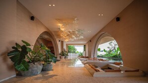 A spacious lobby with a reflective floor, large potted plants, and a seating area with cushions. - Noema Resort Pererenan Bali (Pererenan)