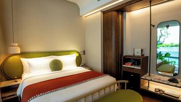 A modern hotel room with a bed, bedside table, nightstand, and a mirror with a view of greenery.