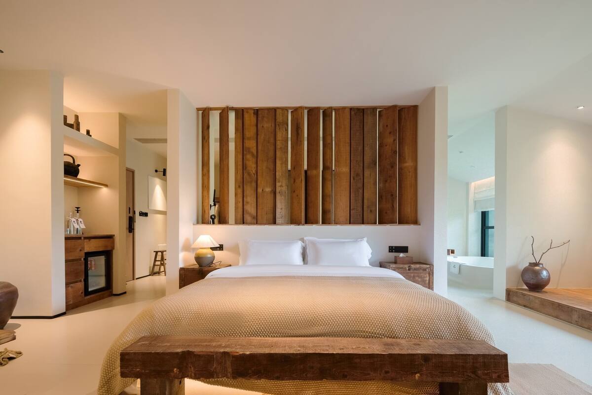 A modern bedroom with a large bed, wooden headboard, bedside tables, and a nightstand.