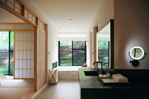 Ein modernes Badezimmer mit großem Fenster, einem Waschbecken und einem Spiegel mit runder Beleuchtung.