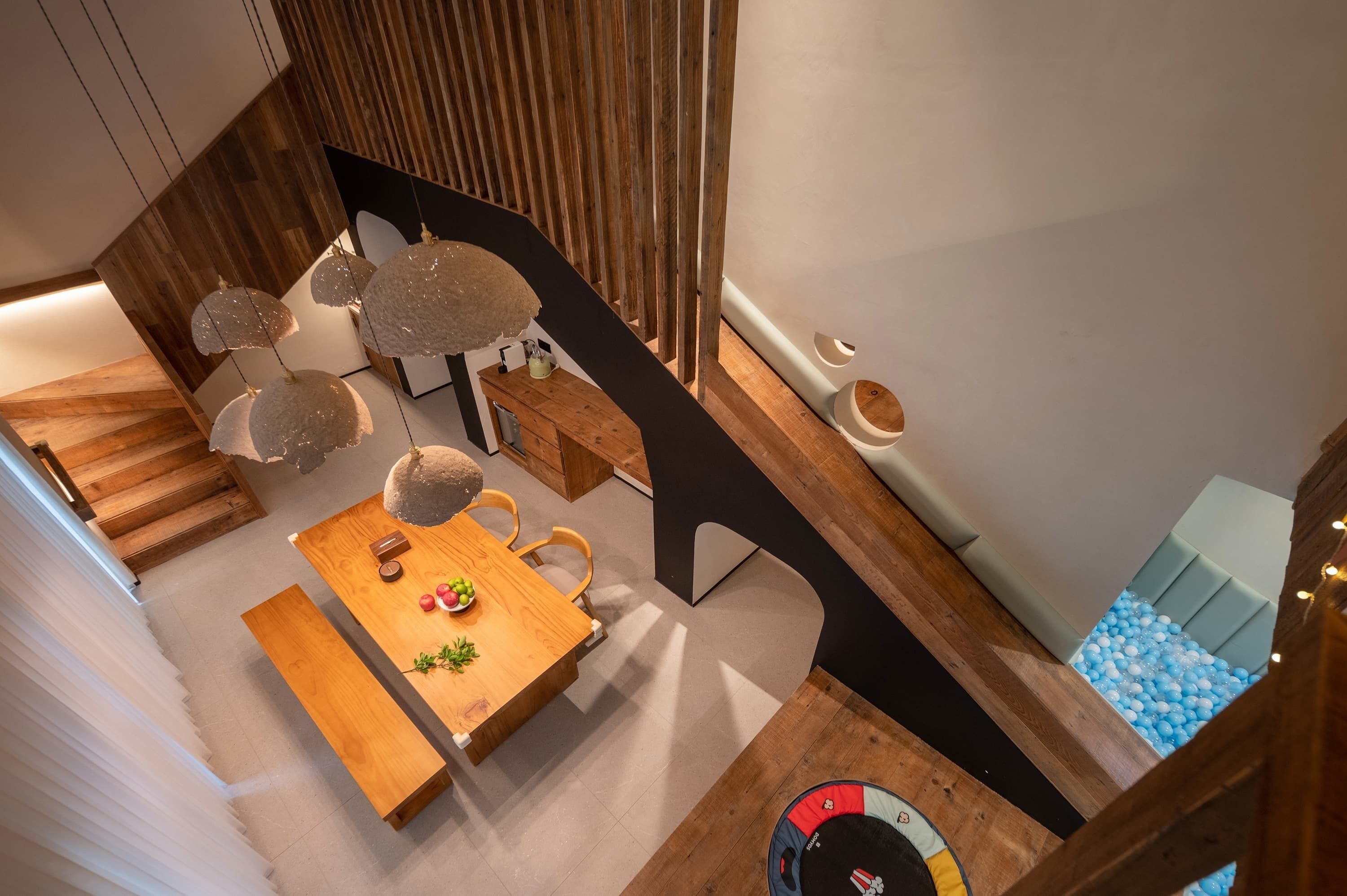 A modern interior with a wooden dining table, chairs, and a hanging light fixture.