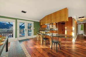 A modern kitchen with a glass island, wooden cabinets, and a view of the outdoors. - 6k sq/ft Mansion! Heated Pool, Hot Tub, Game Room, Theatre, Unforgettable Views! (Colorado Springs)