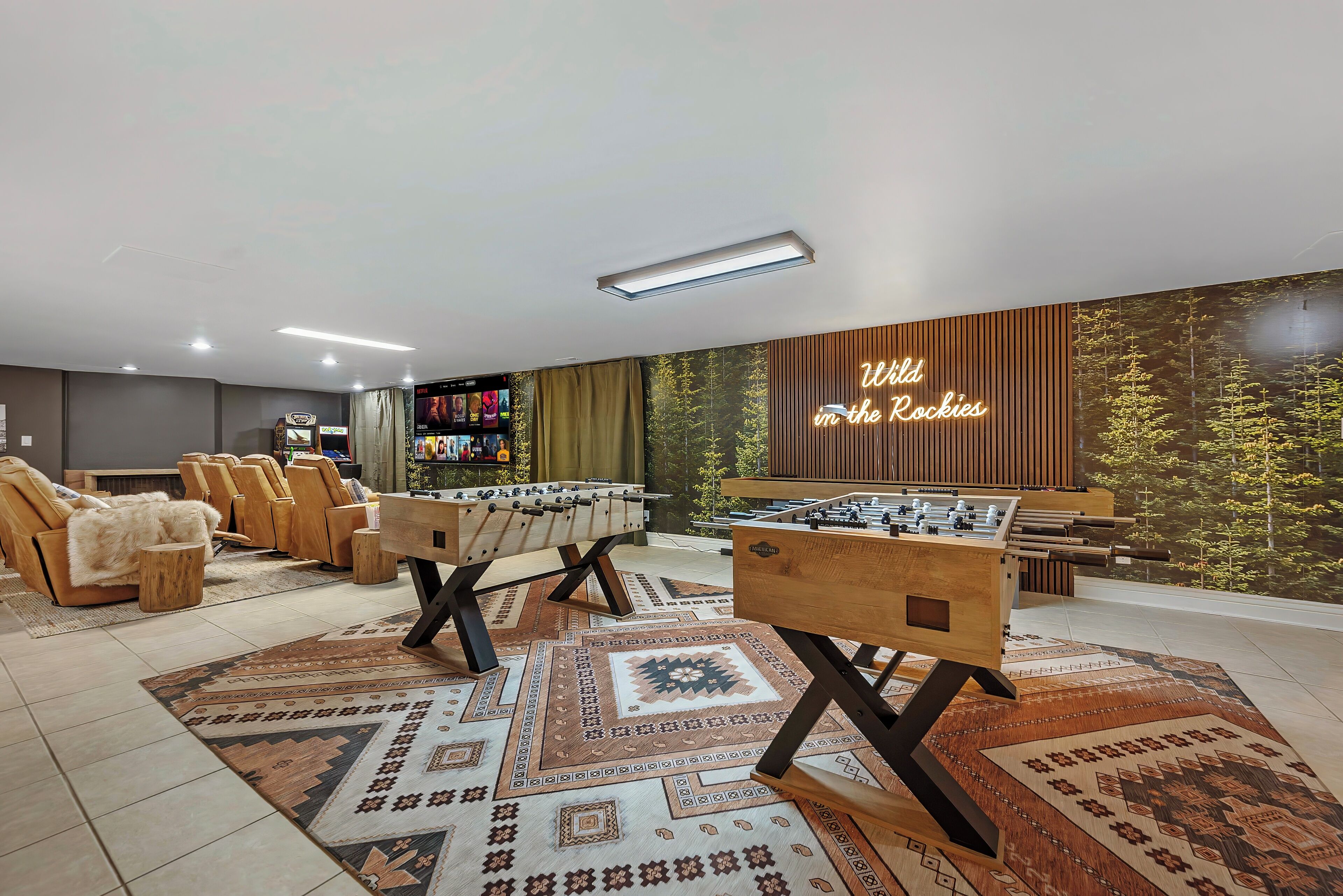 A modern indoor space with two foosball tables, a sofa area, and a wall with a 'Wild in the Rockies' sign.
