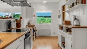 Eine moderne Küche mit weißen Schränken, einer Holzausziehtafel und einem Fenster mit Blick auf eine grüne Wiese.