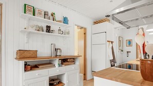 Eine Küche mit weißen Schränken, Holz Arbeitsplatten und Regalen mit verschiedenen Küchenutensilien.