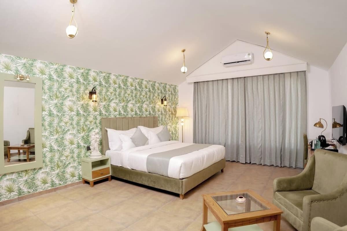 A bedroom with a bed, bedside tables, a mirror, a lamp, a chair, and a TV.