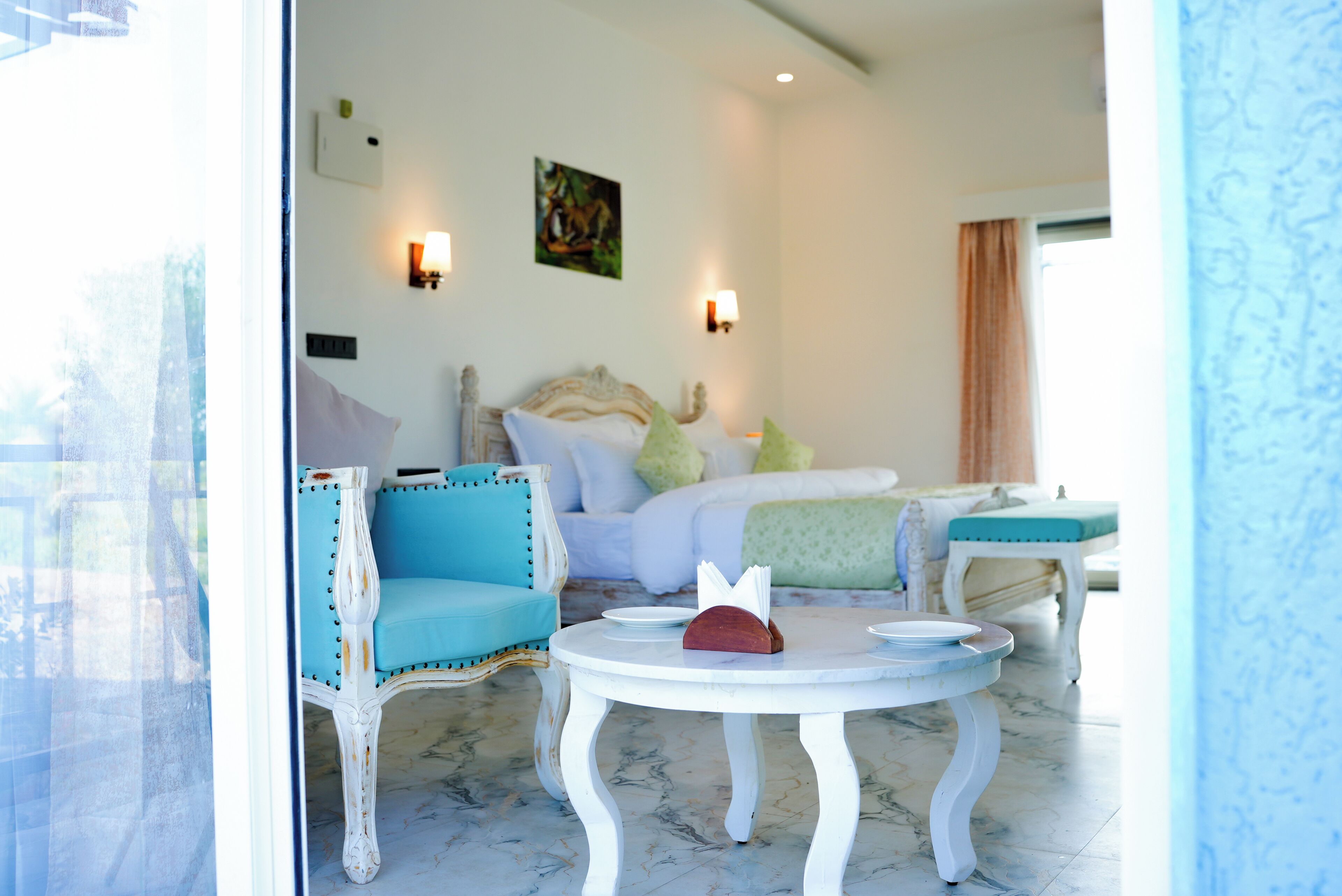 Una habitación con una cama, dos sillas, una mesa y un cuadro en la pared.