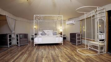 Un dormitorio con cama blanca, dosel, tocador con espejo y suelo de madera.