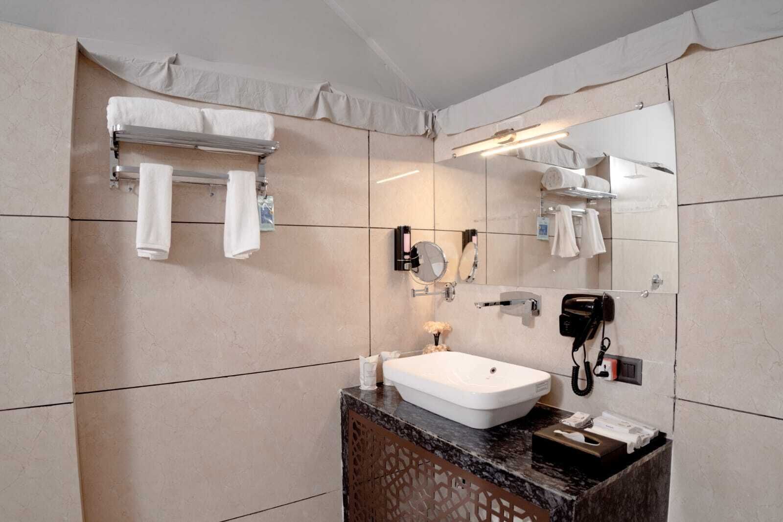 A modern bathroom with a large mirror, a white sink, and a towel rack.