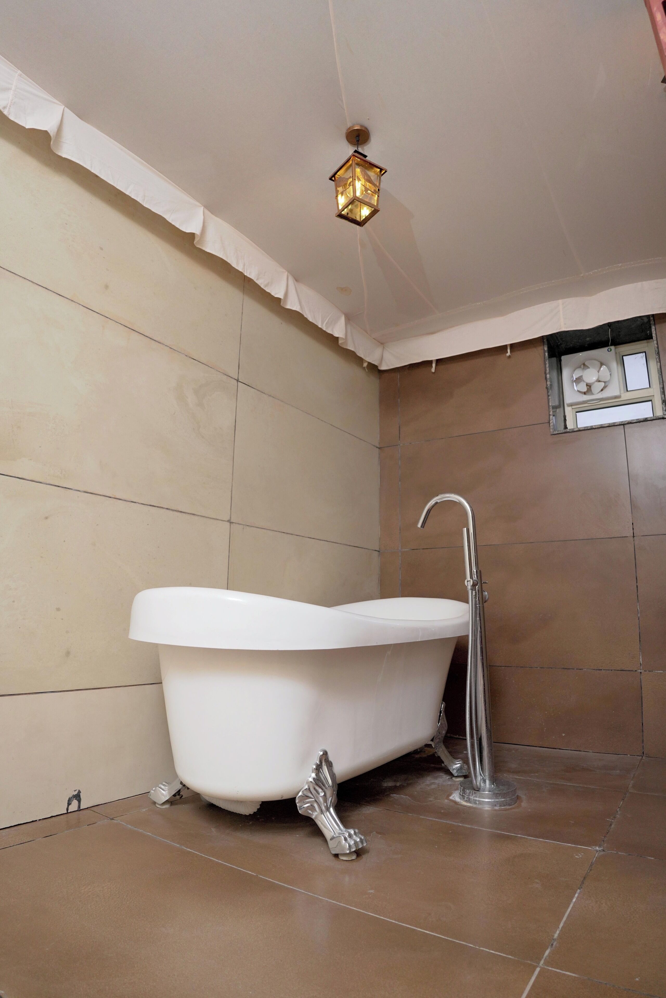 Ein Badezimmer mit einer freistehenden Badewanne, einem Wandventilator und einer dekorativen Leuchte.