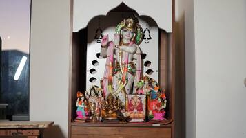 A shrine with a deity figure, small figurines, and a mirror.