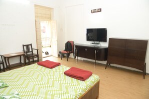 A hotel room with a bed, a desk, a chair, a television, and a wardrobe. - Birla Ayurveda Nashik Stay Center (Nashik)