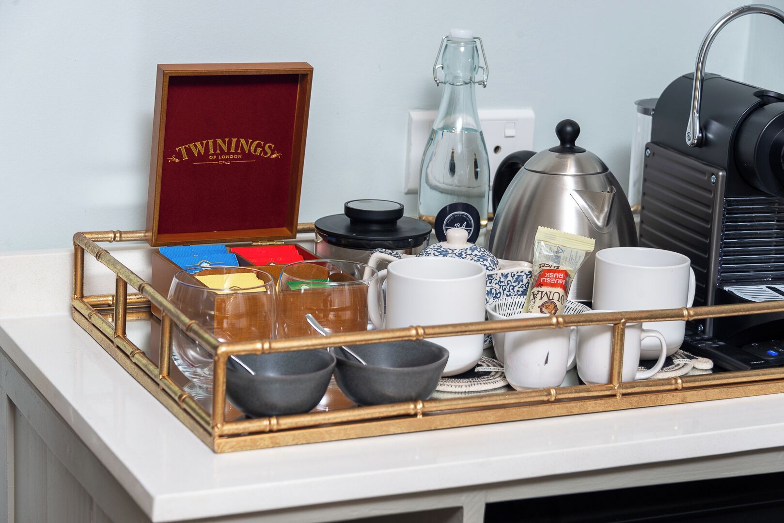 A tray with a variety of coffee-making equipment and containers, including a coffee pot, a grinder, and several mugs.