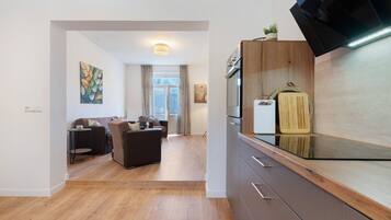 Eine moderne Küche mit Einbauofen, einer Holzausziehtafel und einem kleinen Topf mit Pflanze auf der Arbeitsfläche.