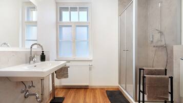 Ein Badezimmer mit Waschbecken, Spiegel, Fenster, Dusche und Handtuchhalter.