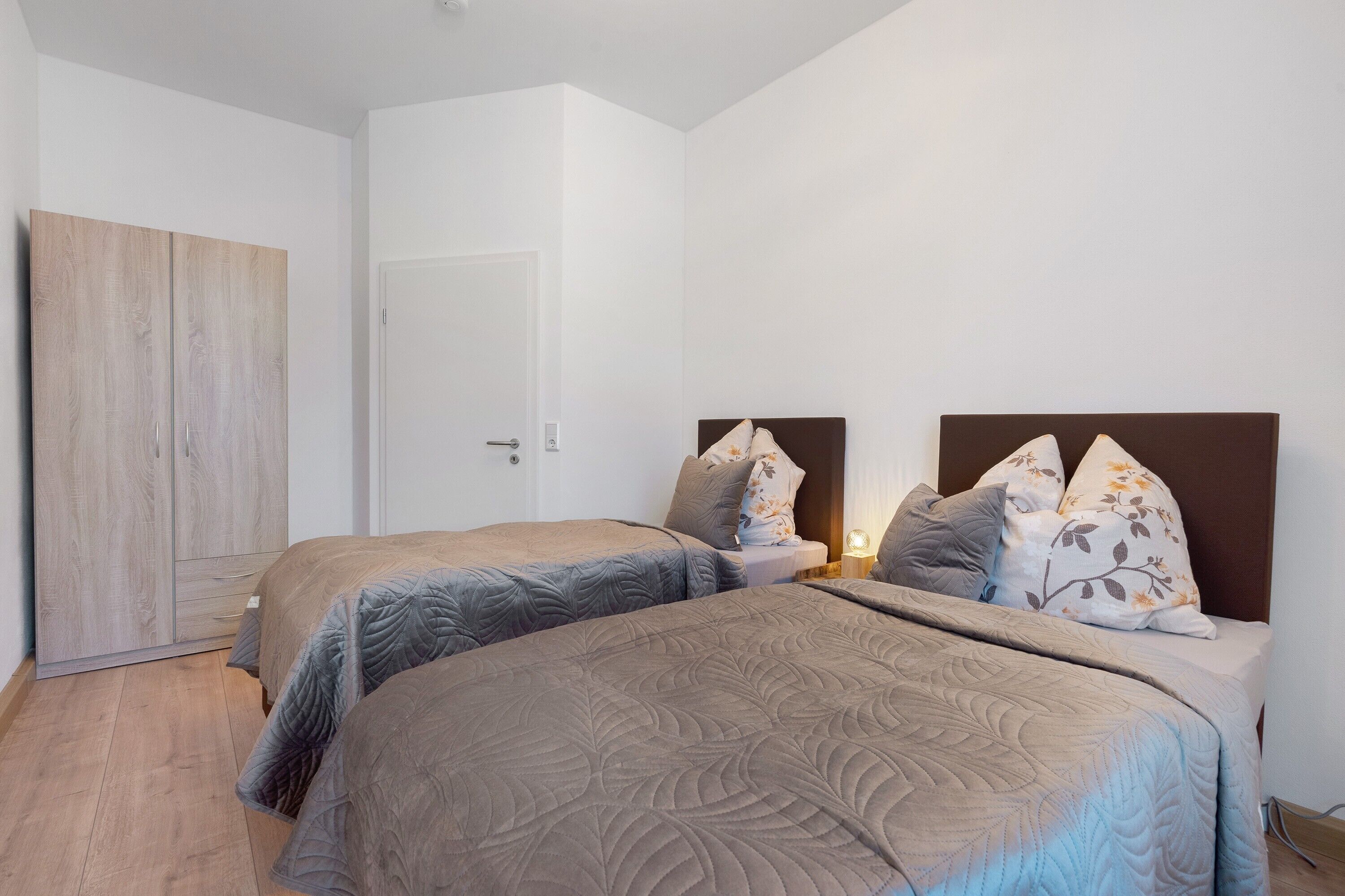 Une chambre avec deux lits, une armoire et une porte.