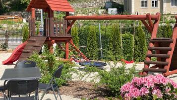 Ein Spielplatz mit Rutsche, Schaukeln und einer Kletteranlage.