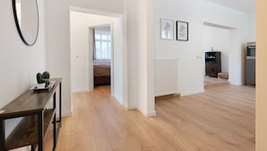 A spacious room with a wooden floor, a dark wooden table, a mirror, and a doorway leading to another room. - Apartment '2' with Private Terrace, Shared Garden and Wi-Fi (Rathmannsdorf)