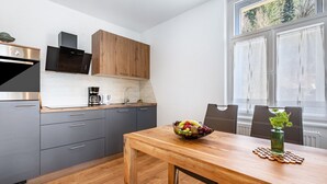 Een moderne keuken met grijze kastjes, een houten eettafel en een schaal fruit.