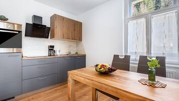 Eine moderne Küche mit grauen Schränken, einem Holztisch und einer Obstschale.