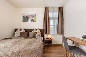 A bedroom with a bed, a desk, a chair, a radiator, and a window with curtains. - Apartment '4' with Shared Garden and Wi-Fi (Rathmannsdorf)