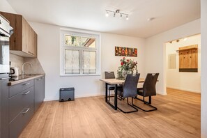 A modern kitchen with grey cabinets, a wooden countertop, and a dining area with a table and chairs. - Apartment '4' with Shared Garden and Wi-Fi (Rathmannsdorf)