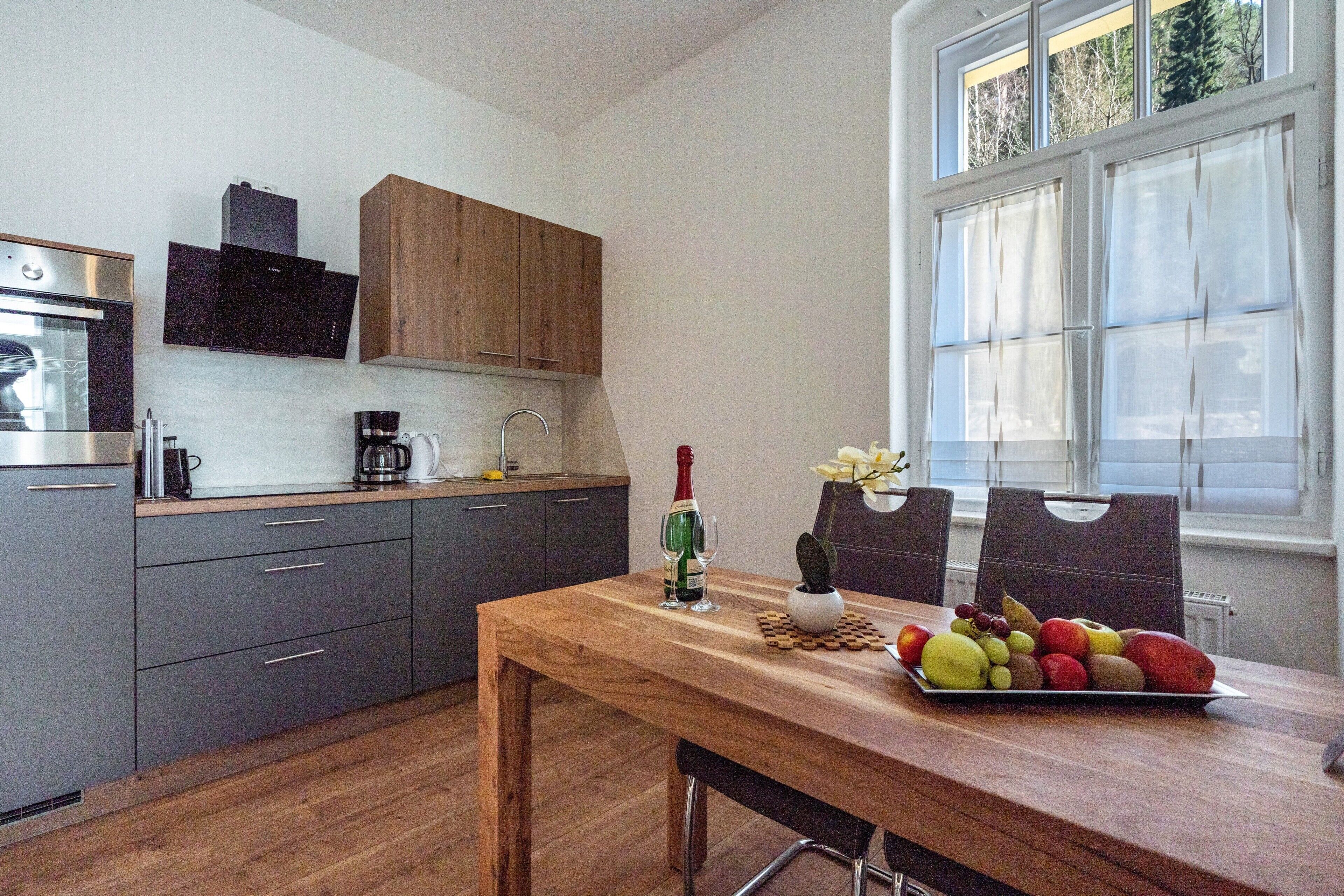 Eine moderne Küche mit grauen Schränken, einem Holztisch und einer Obstplatte.