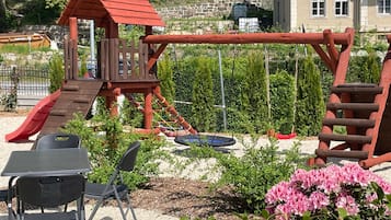 Ein Spielplatz mit Rutsche, Schaukeln und einer Kletteranlage.