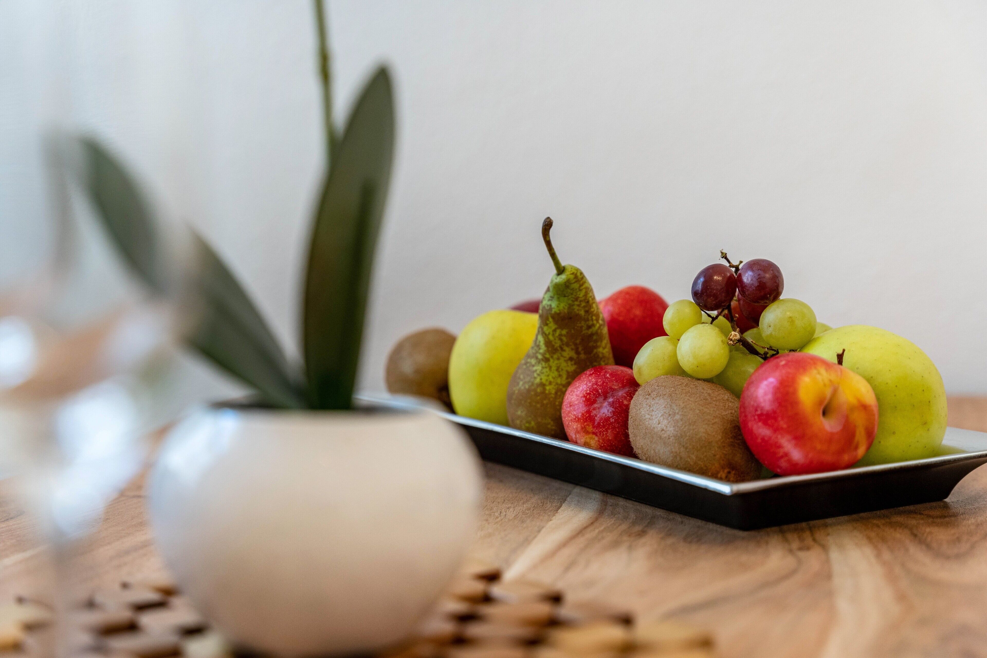 A fruit platter on a tray with a potted plant nearby.