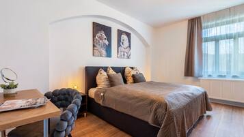 Ein Schlafzimmer mit einem Bett, einem Schreibtisch, einem Sessel und zwei an der Wand befestigten Kunstwerken.
