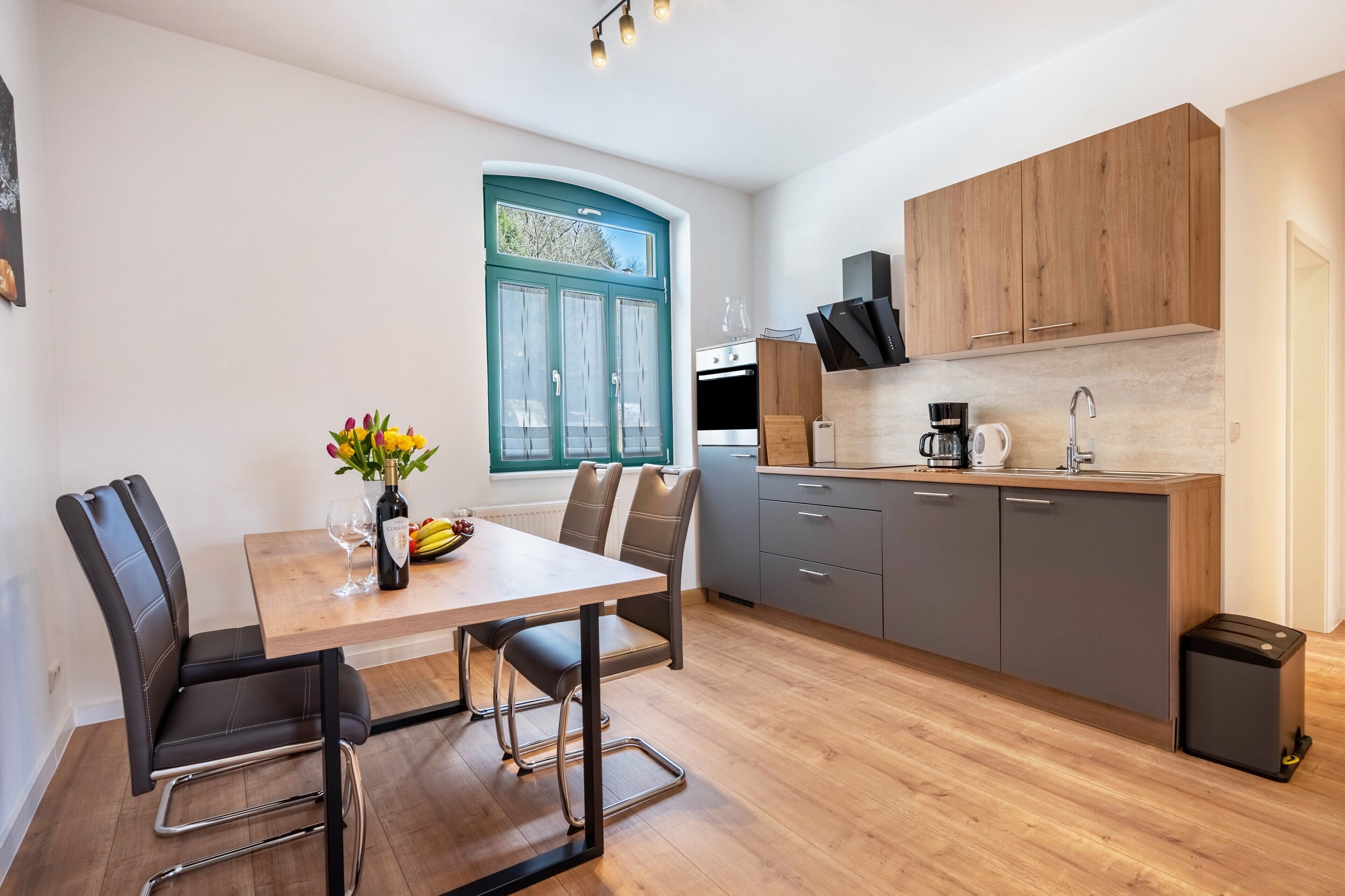 A modern kitchen with a dining area, wooden cabinets, and a window with a view.