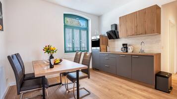 A modern kitchen with a dining area, wooden cabinets, and a window with a view.